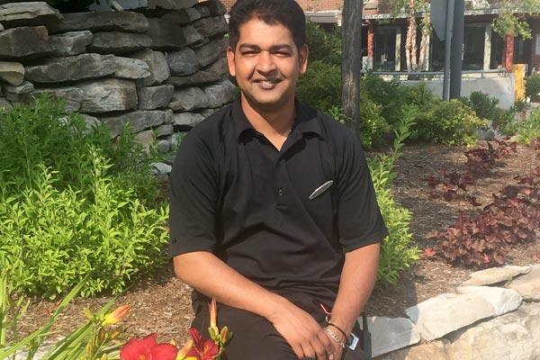 Photo of Golam sitting on a rock wall outside